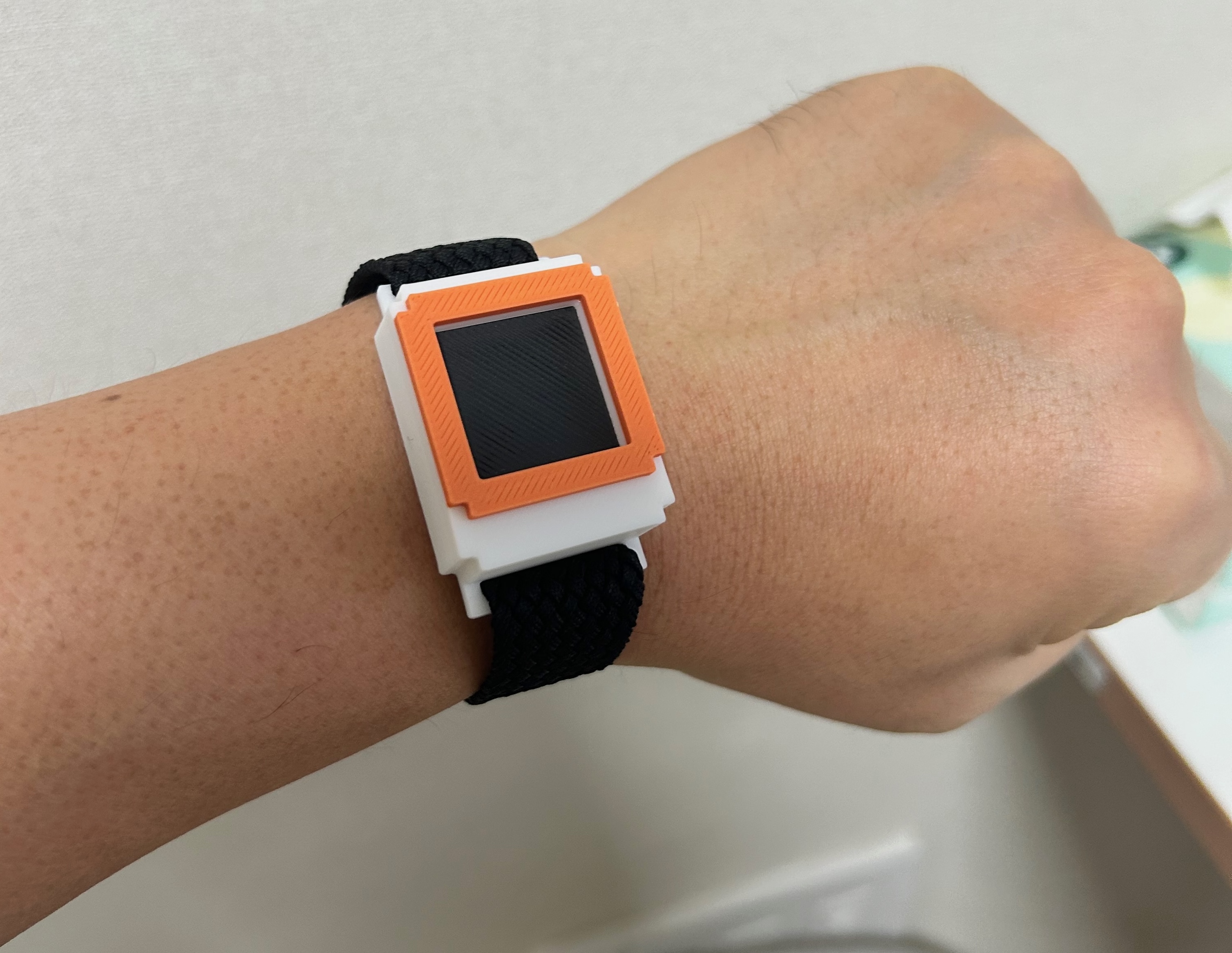 Orange Empix prototype on a wrist outdoors, with its always-on display visible